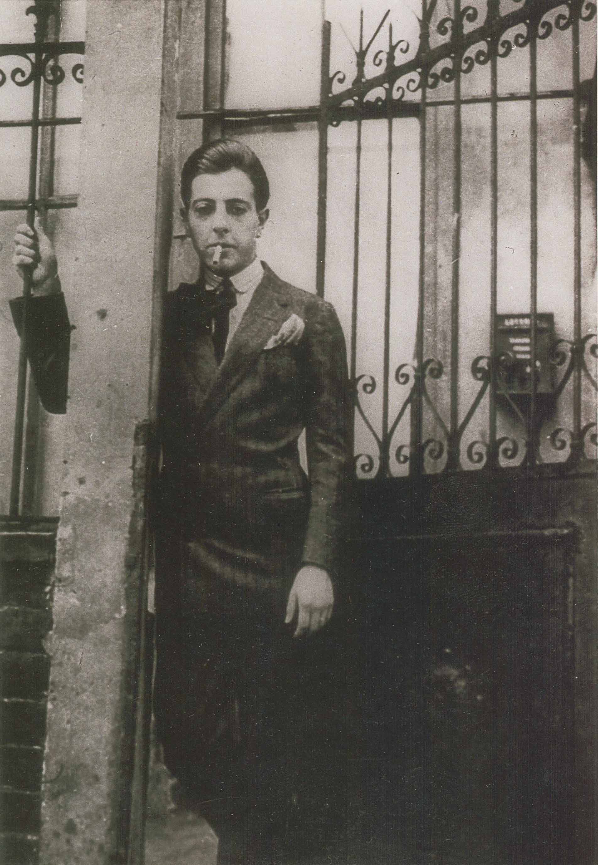 Jacques Prévert posant devant la grille de la rue du Château D.R.