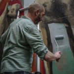 Philippe Hérard applique le rouleau sur un mur de la rue des Couronnes par J Barret