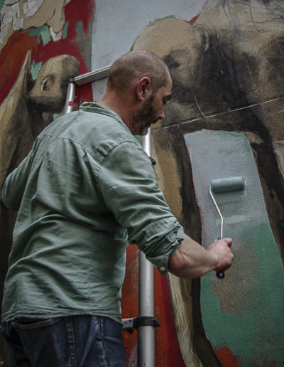 Philippe Hérard applique le rouleau sur un mur de la rue des Couronnes par J Barret