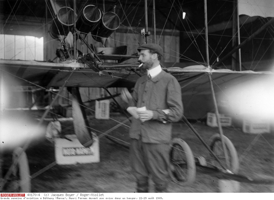 Grande semaine d'aviation à Bétheny (Marne). Henri Farman devant son avion dans un hangar, 22-29 août 1909.
