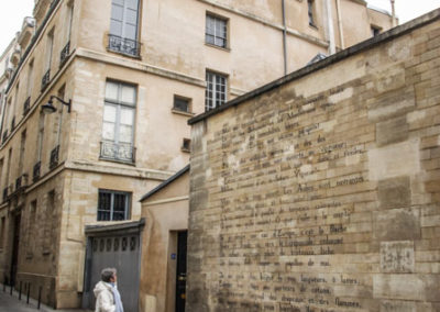 Une femme lisant la fin du poème de Rimbaud, Le Bateau ivre, reproduit à côté de l'atelier de Man Ray sur un mur de la rue Férou, mars 2022 @J.Barret